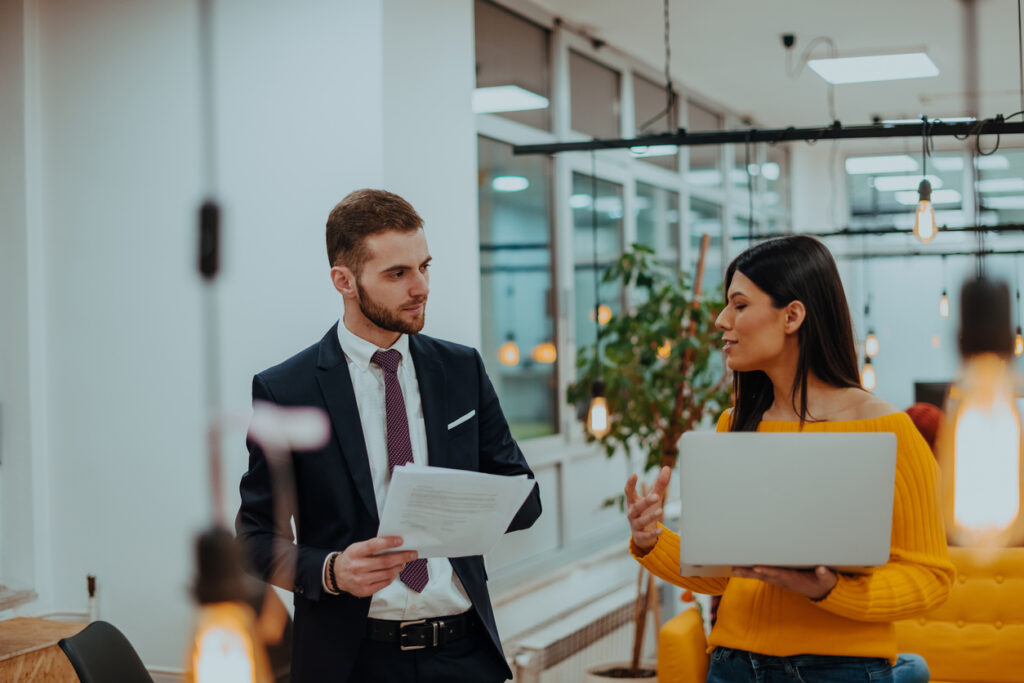 The boss of the company talking to his employee while she shows him the final report on the laptop